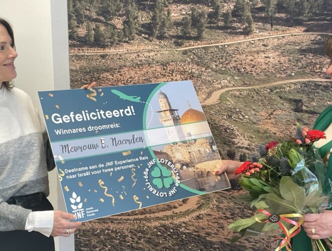 Hoofdprijs winnaar Elly Naarden ontvangt cheque en bloemen